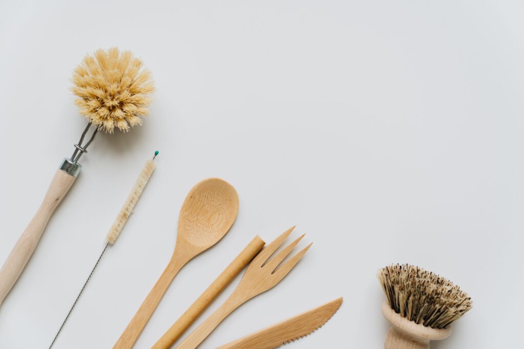 Flat lay of wooden kitchen utensils and brushes promoting eco-friendly lifestyle and sustainability.