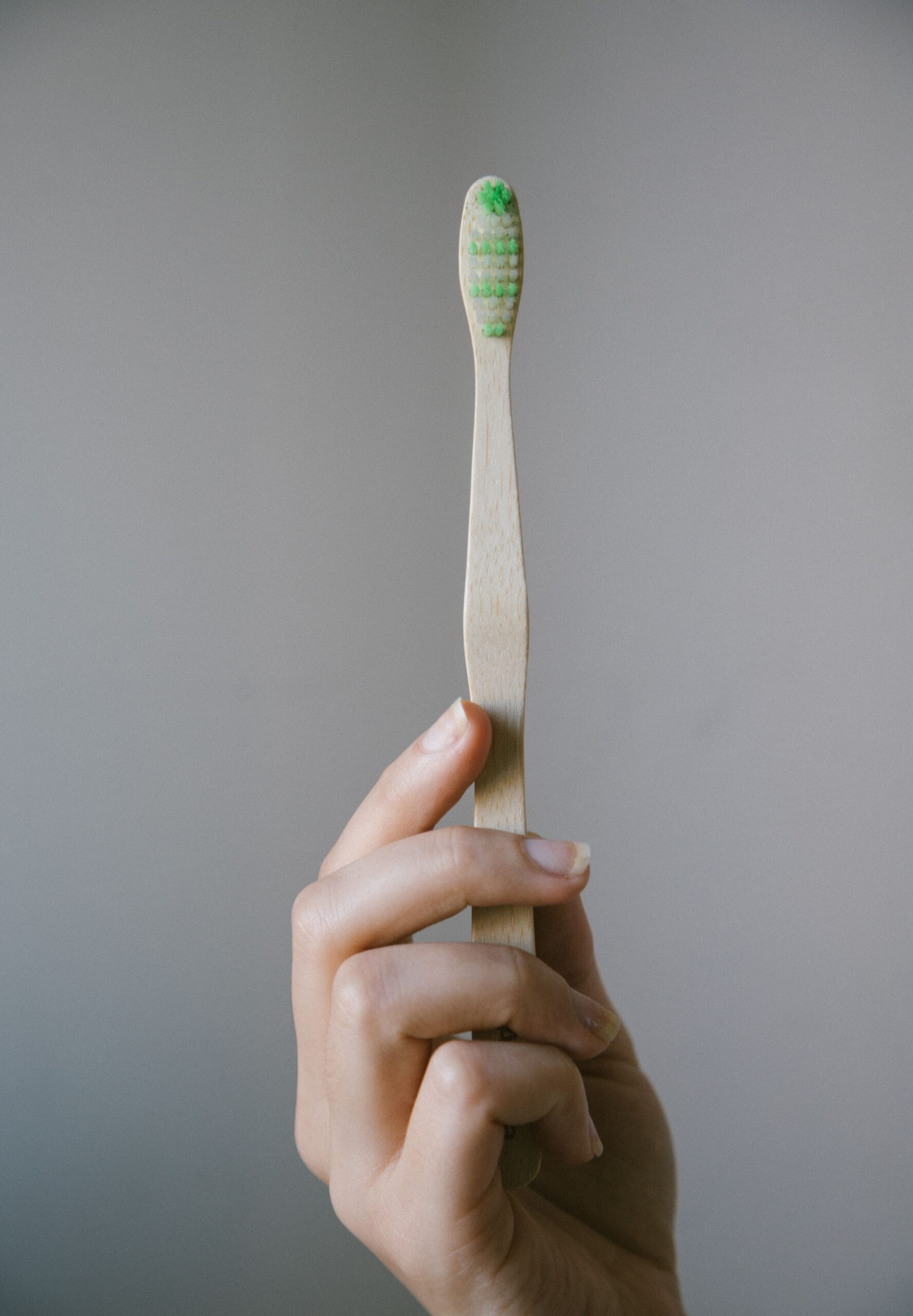 Close-up of a hand holding a bamboo toothbrush for sustainable dental hygiene.